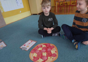 Chłopcy prezentują swoją pizzę ułożoną zgodnie z podanymi składnikami