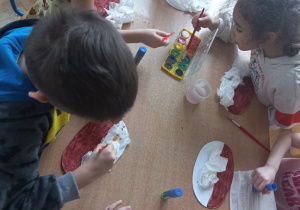 Dzieci malują farbami posypkę na papierowych pączkach
