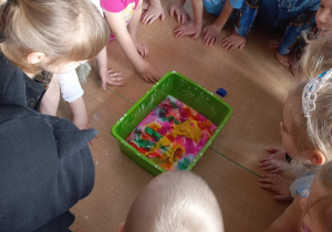 Dzieci obserwują powstający obraz na masie po wrzuceniu kolorowej bibuły