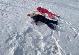 Dzieci bawią się na śniegu w ogrodzie przedszkolnym