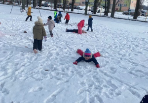 Dzieci bawią się na śniegu w ogrodzie przedszkolnym