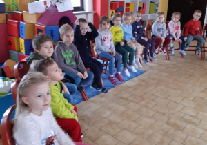 Dzieci siedzą na krzesłach i słuchają opowiadań o szkole