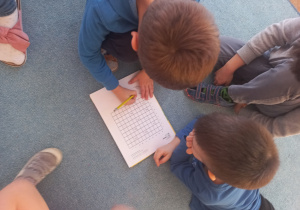 Chłopcy wypisują koordynaty na których znajdują się dinozaury