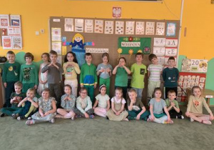 Grupowe zdjęcie dzieci ubranych na zielono w sali przedszkolnej.