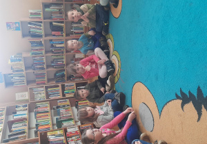 Dzieci siedzą na dywanie I słuchają wierszy
