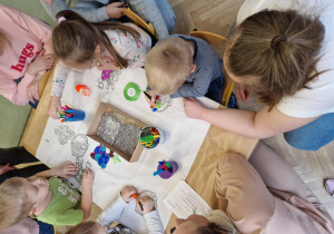 Dzieci kolorują mazakami świąteczne witrażyki