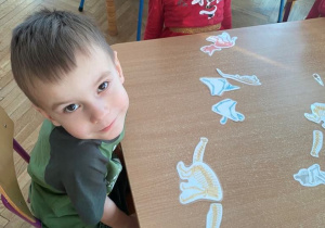 Chłopiec układa szkielet dinozaura z papieru