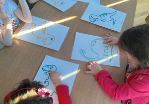 Dzieci kreślą palcem po śladzie dinozaura
