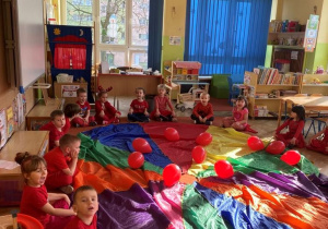 Dzieci bawią się chustą animacyjną i czerwonymi balonami