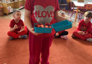 Dziewczynka pozuje do zdjęcia z czerwonymi owocami - truskawkami