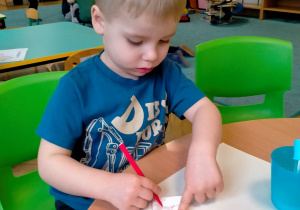 chłopiec koloruje kartkę mazakami