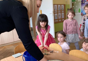 Dzieci obserwują jak nauczycielka wyrabia masę solną