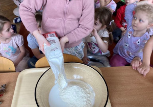 Dziewczynka wsypuje mąkę do miski aby zrobić masą solną