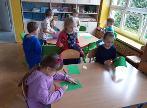Dzieci rysują i wycinają szczypiorek dla cebuli z zielonego kartonu