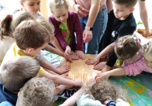 Dzieci odciskają wodę z uformowanej masy papierowej za pomocą dużej deski i ściereczek