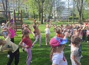 Dzieci wykonują skłony boczne podczas wspólnej rozgrzewki w ogrodzie przedszkolnym