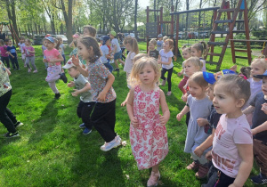 Dzieci biegną w miejscu podczas wspólnej rozgrzewki w ogrodzie przedszkolnym
