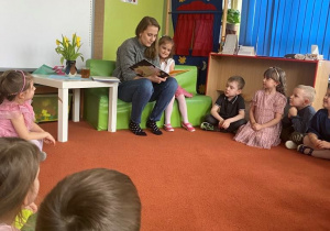 Mama czyta książkę dzieciom siedzącym na dywanie