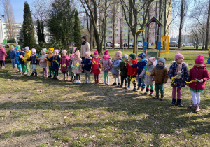 Dzieci stojąc w kole w przedszkolnym ogrodzie świętują pierwszy dzień wiosny