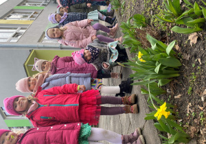 Dzieci oglądają wiosenne kwiaty w przedszkolnym ogrodzie