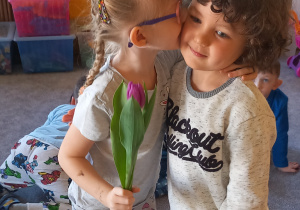 Dziewczynka daje całusa koledze w policzek w ramach podziękowań za otrzymany kwiatek