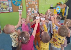 Dzieci łapią bańki mydlane do kubeczków.