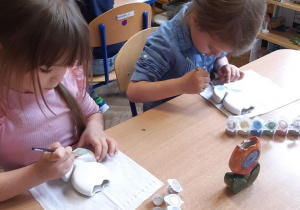Dziewczynki malują ceramiczne kwiatki