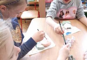 Dziewczynki malują ceramiczne kwiatki