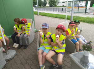 Dzieci ze smakiem jedzą lody siedząc w lodziarni.