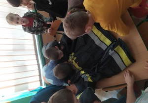 Dzieci oglądają mundur bojowy strażaka.