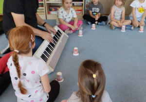 Dzieci słuchają piosenki śpiewanej przez prowadzącego, którą potem powtórzą
