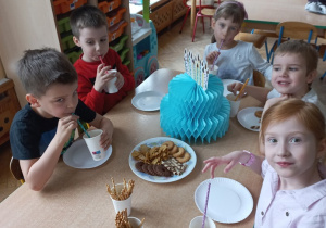 Dzieci siedzą przy urodzinowym stole