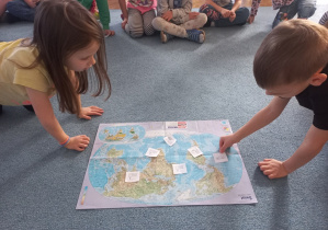 Dzieci układają ilustracje na mapie