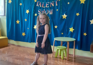 Dziewczynka stoi na scenie i śpiewa piosenkę