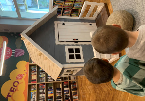 Dzieci oglądają domek w kąciku przeznaczonym dla najmłodszych czytelników biblioteki "TEOteka"