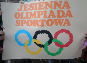 Dzieci trzymają plakat jesiennej olimpiady sportowej