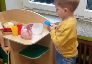 chłopiec bawi się w kąciku lalek