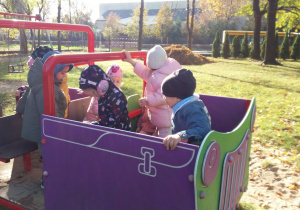 dzieci bawią sie w drewnianym samochodzie