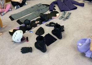 dzieci oglądają akcesoria snowboardowe