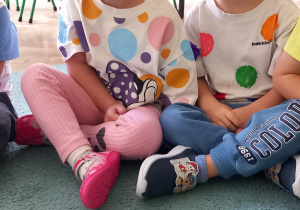 Dzieci ubrane w bluzki w kropki siedzą obok siebie w siadzie skrzyżnym