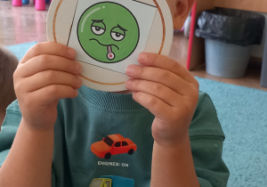 Dziecko pokazuje emblemat z kropką