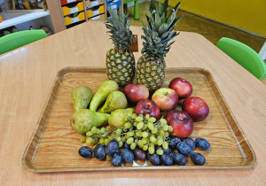 ananas, jabłka, gruszki, śliwki oraz wonogrono na tacy