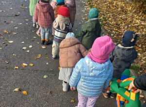 Dzieci idą na spacer trzymając pluszowego węża