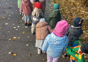 Dzieci idą na spacer trzymając pluszowego węża