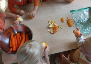 Dzieci obierają pomarańcze i mandarynki