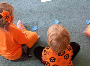 Dzieci siedzą w siadzie skrzyżnym i mają położone przed sobą krople deszczu