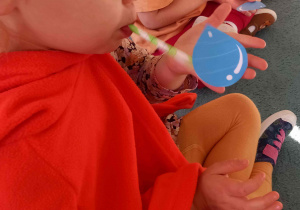 Chłopiec stara się zdmuchnąć przez słomkę kropelkę leżącą na jego dłoni