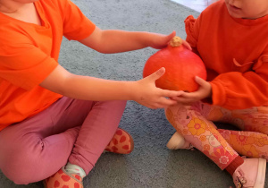 Dziewczynki z rąk do rąk przekładają dynię w rytm muzyki "Podaj dynię"