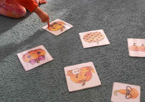 Dziecko wskazuje na kartę, która przedstawia dynię z muchą