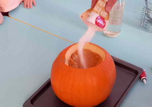 Nauczycielka wsypuje sodę do wnętrza dyni